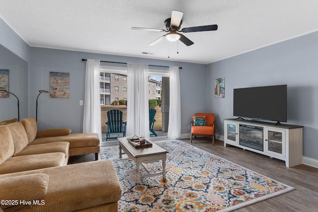 living room featuring visible vents, a ceiling fan, a textured ceiling, wood finished floors, and baseboards