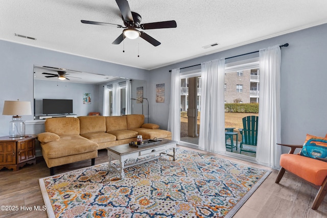 living room with visible vents, crown molding, a textured ceiling, and wood finished floors