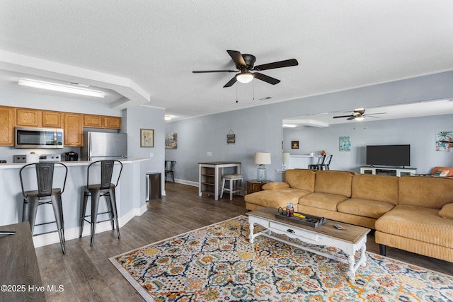 living room with a ceiling fan, dark wood finished floors, a textured ceiling, and baseboards