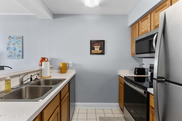 kitchen featuring stainless steel appliances, brown cabinetry, a sink, and light countertops