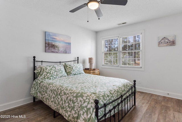 bedroom with baseboards, visible vents, ceiling fan, wood finished floors, and a textured ceiling