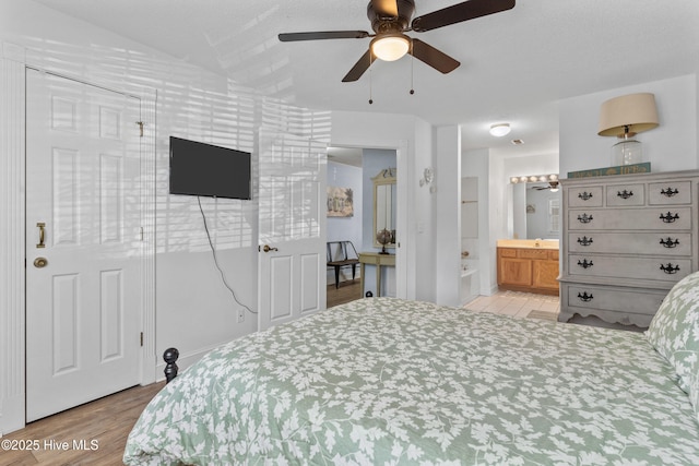 bedroom with wood finished floors, a ceiling fan, and connected bathroom