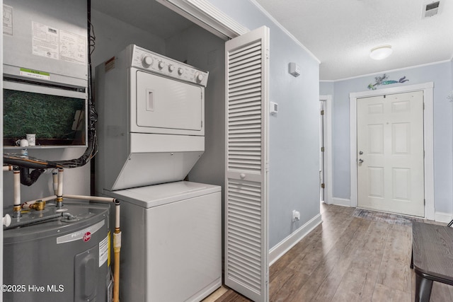 laundry area with electric water heater, laundry area, wood finished floors, visible vents, and stacked washing maching and dryer