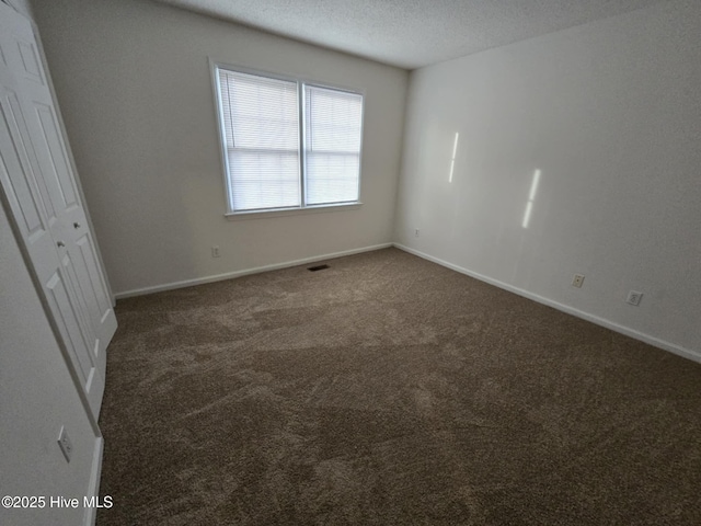 unfurnished bedroom featuring carpet, visible vents, a textured ceiling, and baseboards