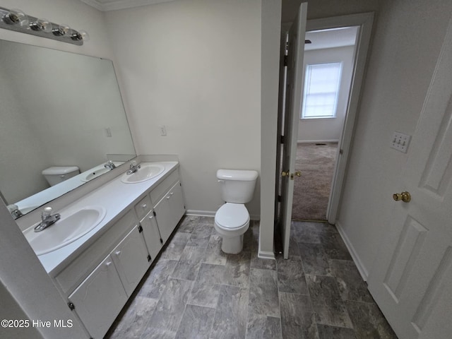 bathroom with double vanity, a sink, and toilet