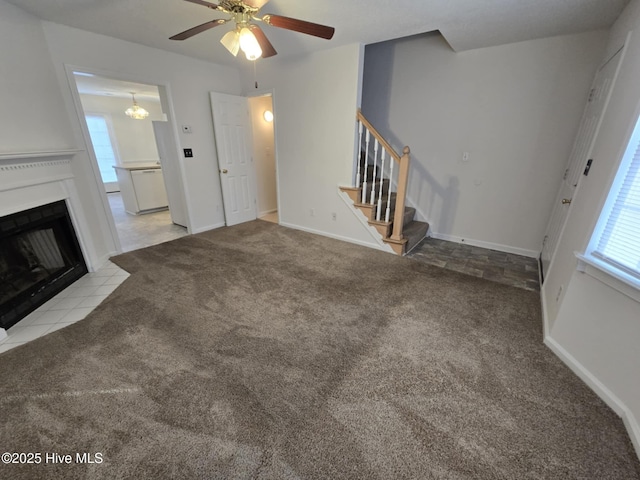 unfurnished living room with a fireplace with flush hearth, carpet flooring, and stairs