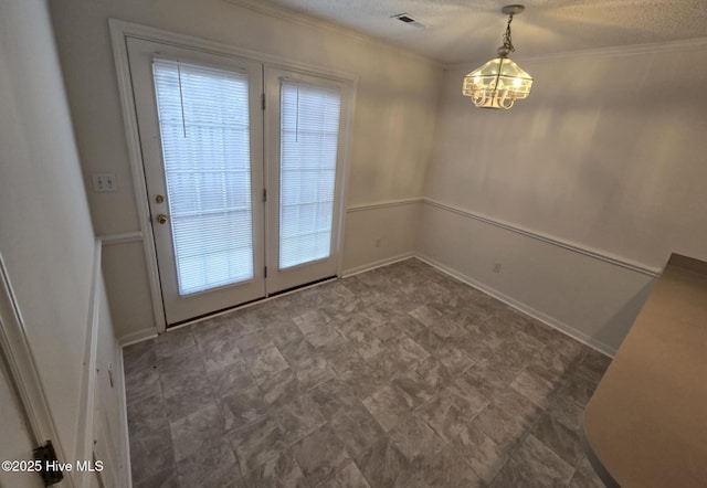 doorway with crown molding, visible vents, an inviting chandelier, a textured ceiling, and baseboards