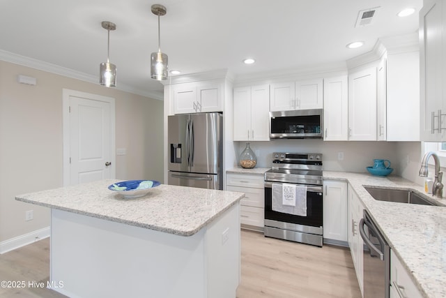 kitchen with visible vents, a sink, white cabinets, appliances with stainless steel finishes, and crown molding