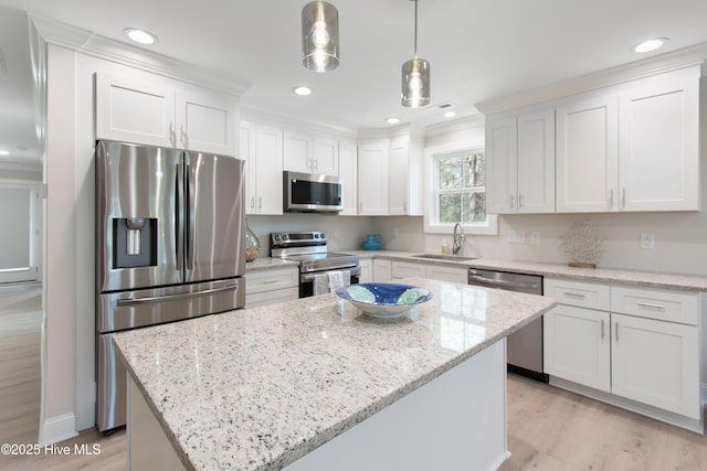 kitchen featuring a sink, hanging light fixtures, appliances with stainless steel finishes, white cabinetry, and a center island