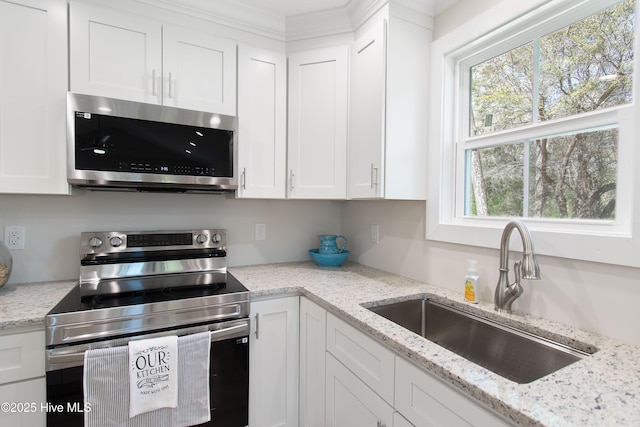 kitchen with a sink, light stone countertops, white cabinetry, and stainless steel appliances