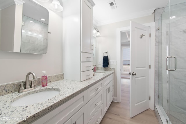 full bath featuring a shower stall, ornamental molding, wood finished floors, and a sink