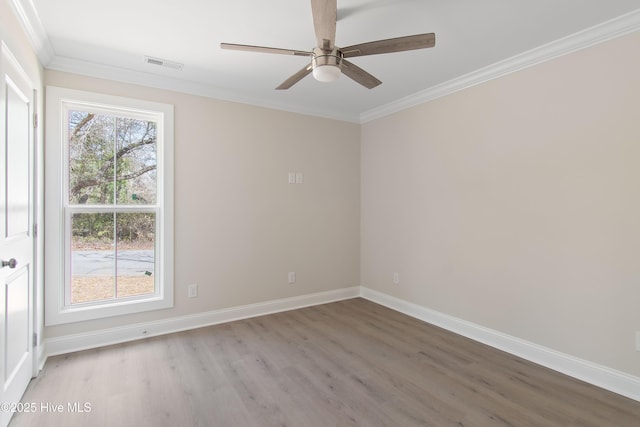 spare room with baseboards, visible vents, light wood-style flooring, ceiling fan, and crown molding