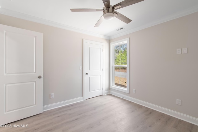 empty room featuring light wood-type flooring, baseboards, and ornamental molding