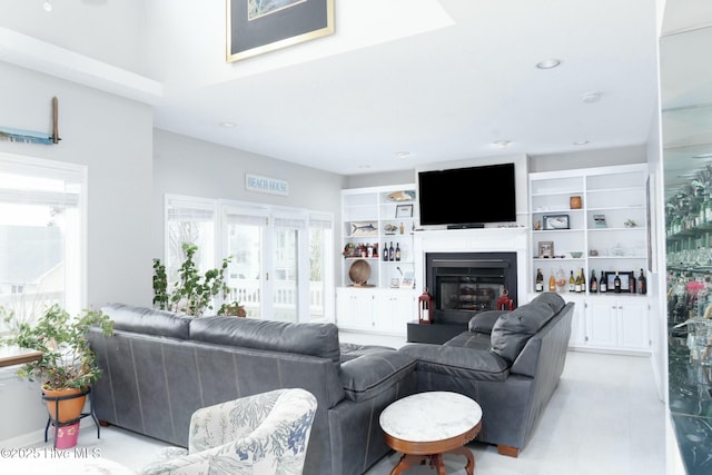 living room featuring a glass covered fireplace, built in shelves, and recessed lighting