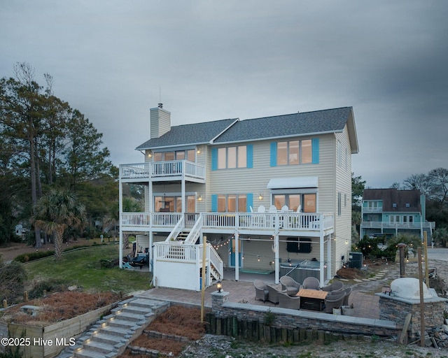 rear view of property with central air condition unit, a patio, stairway, a balcony, and a chimney