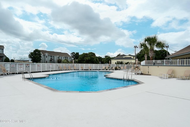 community pool with a patio area and fence