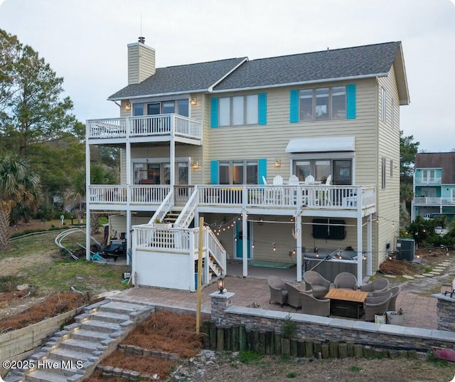 back of house featuring a chimney, a deck, central AC unit, stairs, and a patio area