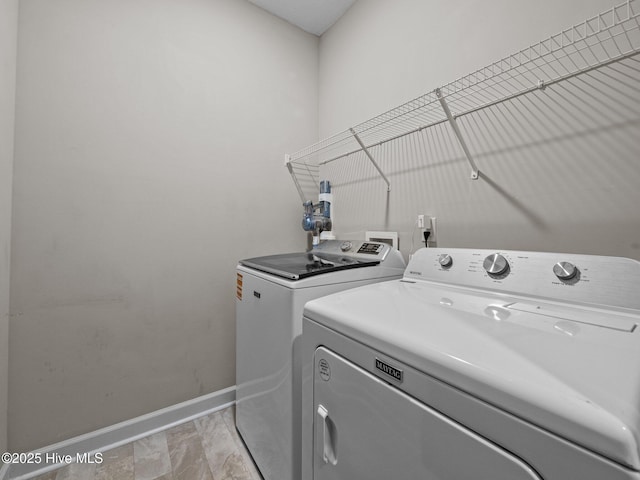 washroom featuring laundry area, baseboards, and washing machine and clothes dryer