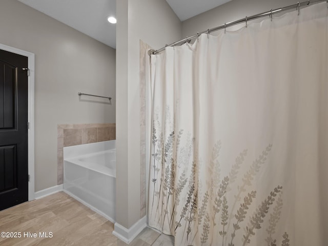 bathroom with baseboards, a garden tub, and wood finished floors