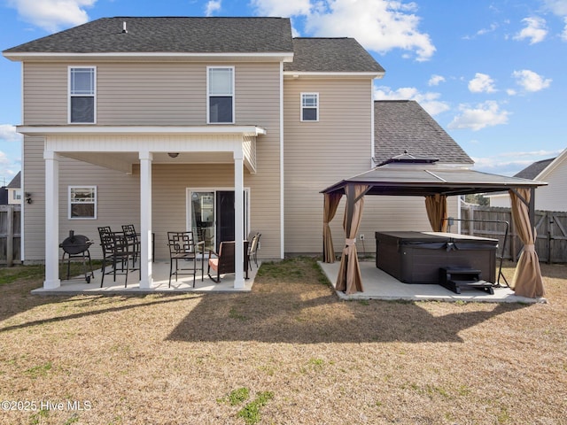 rear view of house featuring fence, a gazebo, a yard, a patio area, and a hot tub