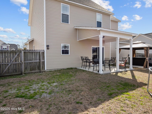 back of house with a gazebo, a patio, fence, and a lawn