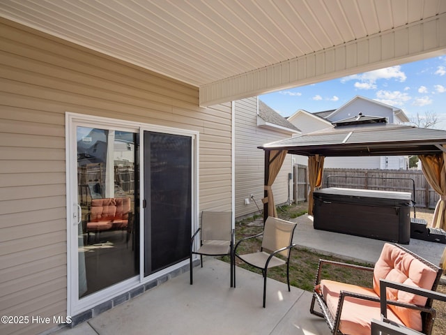 view of patio with a gazebo, a hot tub, and fence