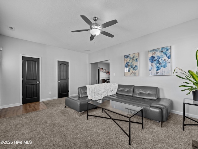 living room featuring visible vents, baseboards, carpet floors, and a ceiling fan