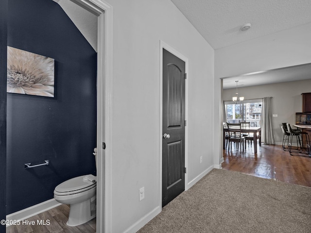 hall with wood finished floors, baseboards, and a textured ceiling