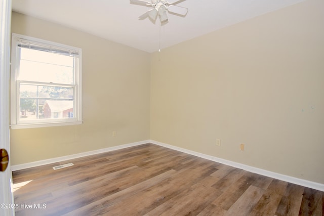 spare room featuring ceiling fan, visible vents, baseboards, and wood finished floors