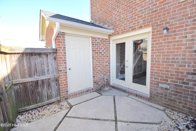 entrance to property with brick siding and a shingled roof