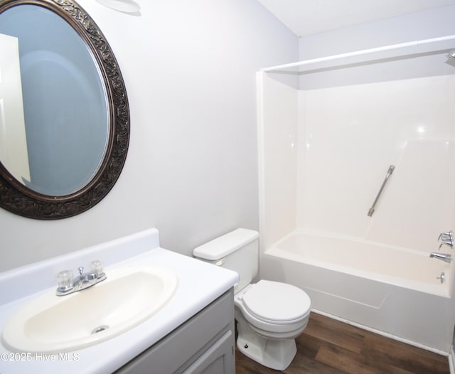 bathroom featuring toilet, tub / shower combination, vanity, and wood finished floors