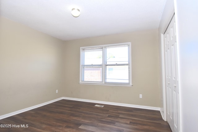 unfurnished bedroom featuring a closet, baseboards, visible vents, and dark wood-style floors