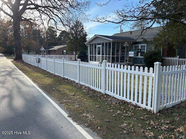 exterior space with a fenced front yard and a sunroom