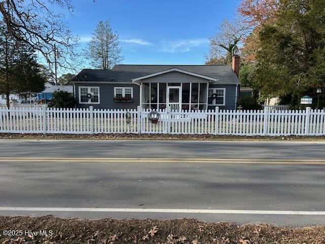 view of front of house featuring a fenced front yard, a chimney, and a sunroom