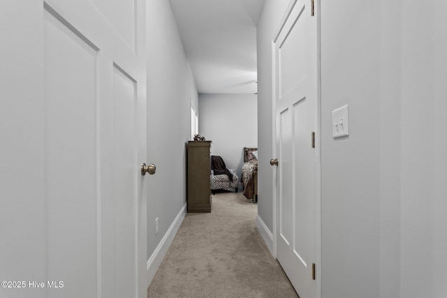 corridor with baseboards and light carpet