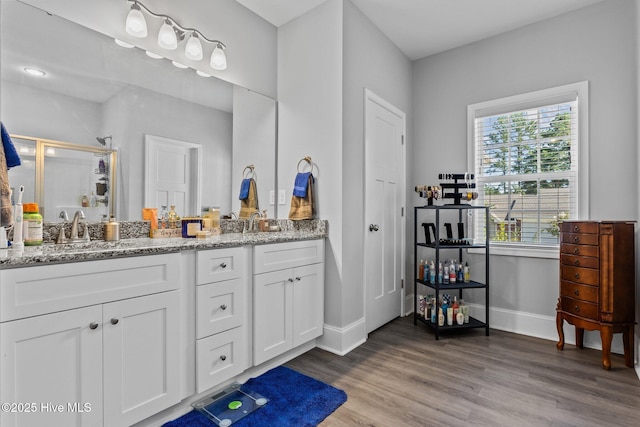 full bath featuring a sink, a shower stall, wood finished floors, and double vanity