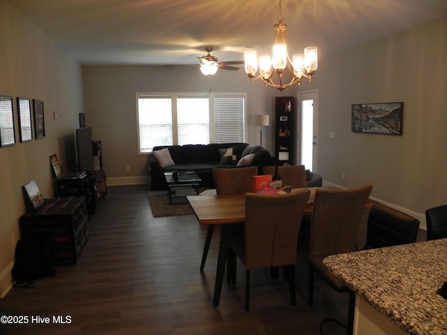 dining room with ceiling fan with notable chandelier, dark wood-type flooring, and baseboards