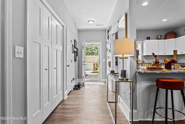 interior space with visible vents, recessed lighting, white cabinets, light wood-style floors, and a kitchen breakfast bar