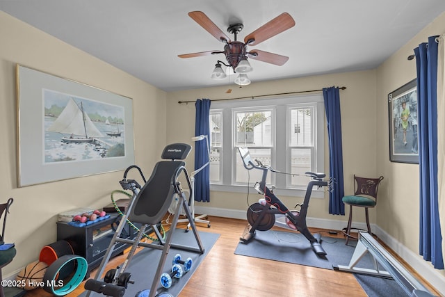 exercise area featuring a ceiling fan, wood finished floors, and baseboards