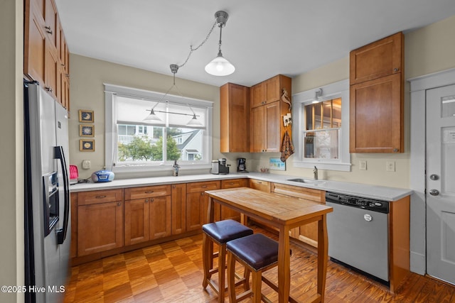 kitchen with decorative light fixtures, brown cabinets, appliances with stainless steel finishes, and light countertops