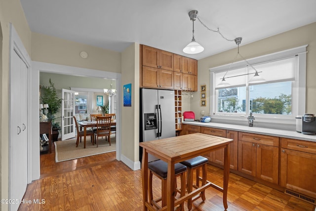 kitchen featuring visible vents, light countertops, brown cabinets, stainless steel refrigerator with ice dispenser, and wood finished floors