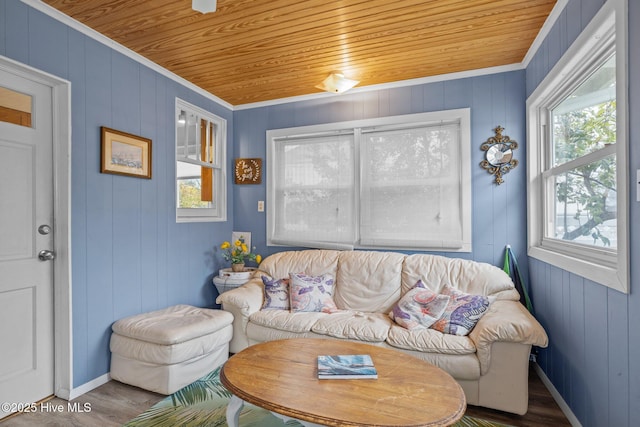 living area with baseboards, wood ceiling, wood finished floors, and ornamental molding