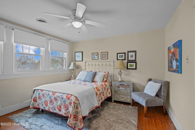 bedroom with visible vents, baseboards, wood finished floors, and a ceiling fan