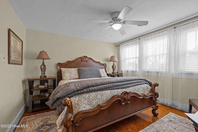 bedroom with multiple windows, wood finished floors, baseboards, and ceiling fan