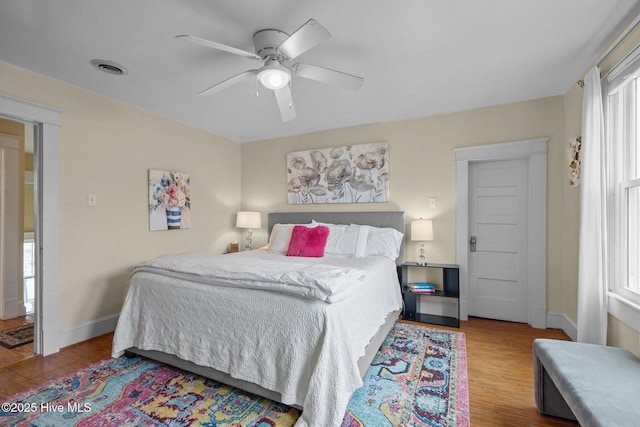 bedroom featuring visible vents, baseboards, ceiling fan, and wood finished floors