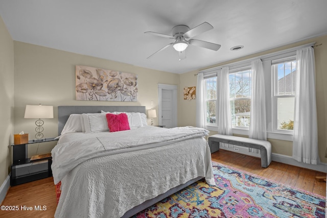 bedroom with ceiling fan, visible vents, baseboards, and hardwood / wood-style floors