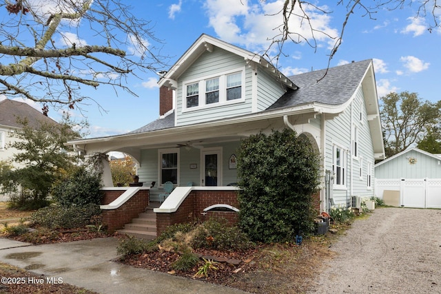 bungalow featuring a garage, covered porch, a ceiling fan, and roof with shingles