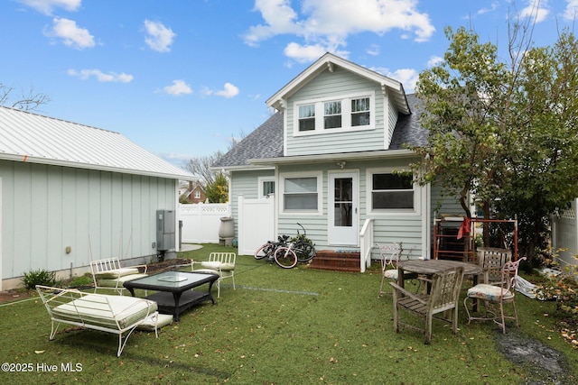 back of house featuring a lawn, a shingled roof, entry steps, and fence