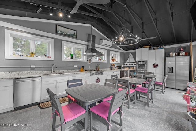 kitchen featuring a sink, appliances with stainless steel finishes, white cabinets, wall chimney range hood, and vaulted ceiling