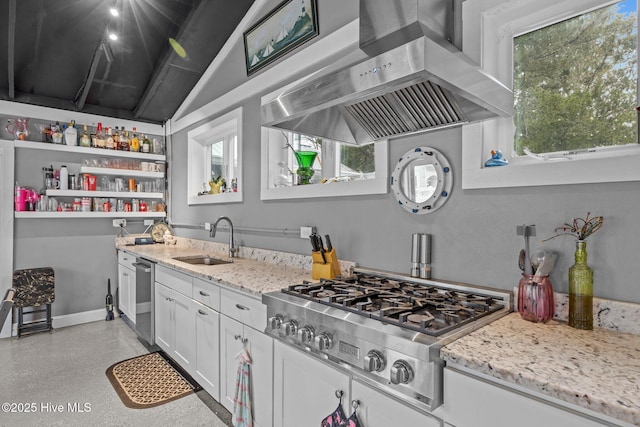 kitchen featuring wall chimney range hood, light stone counters, white cabinets, stainless steel appliances, and a sink